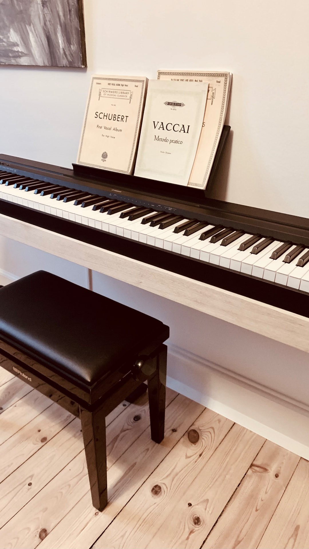 Customer photo of an oak piano frame with vocal sheet music and a black bench on a wooden floor