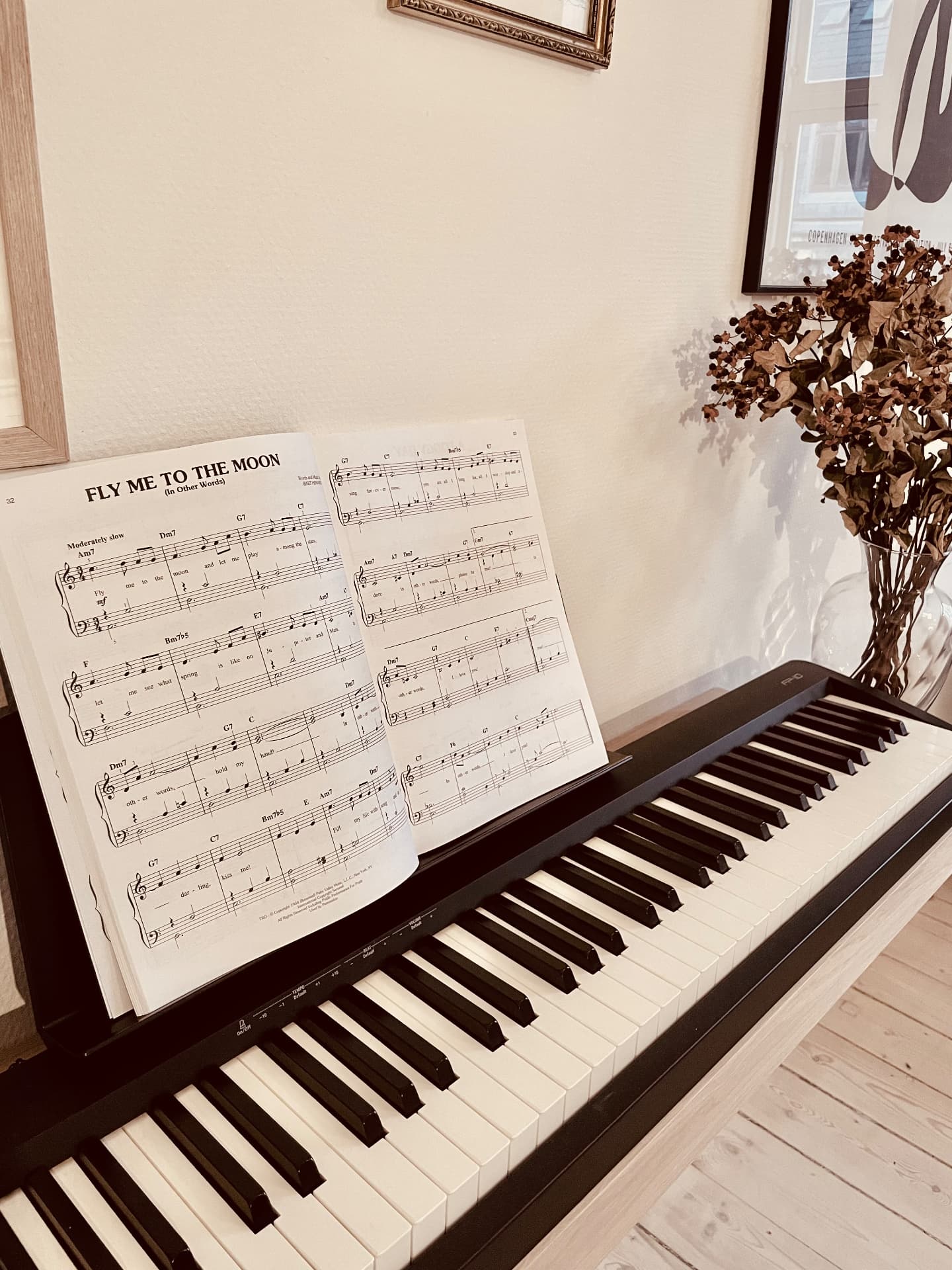 Digital piano resting on an oak wall-mounted frame with open sheet music