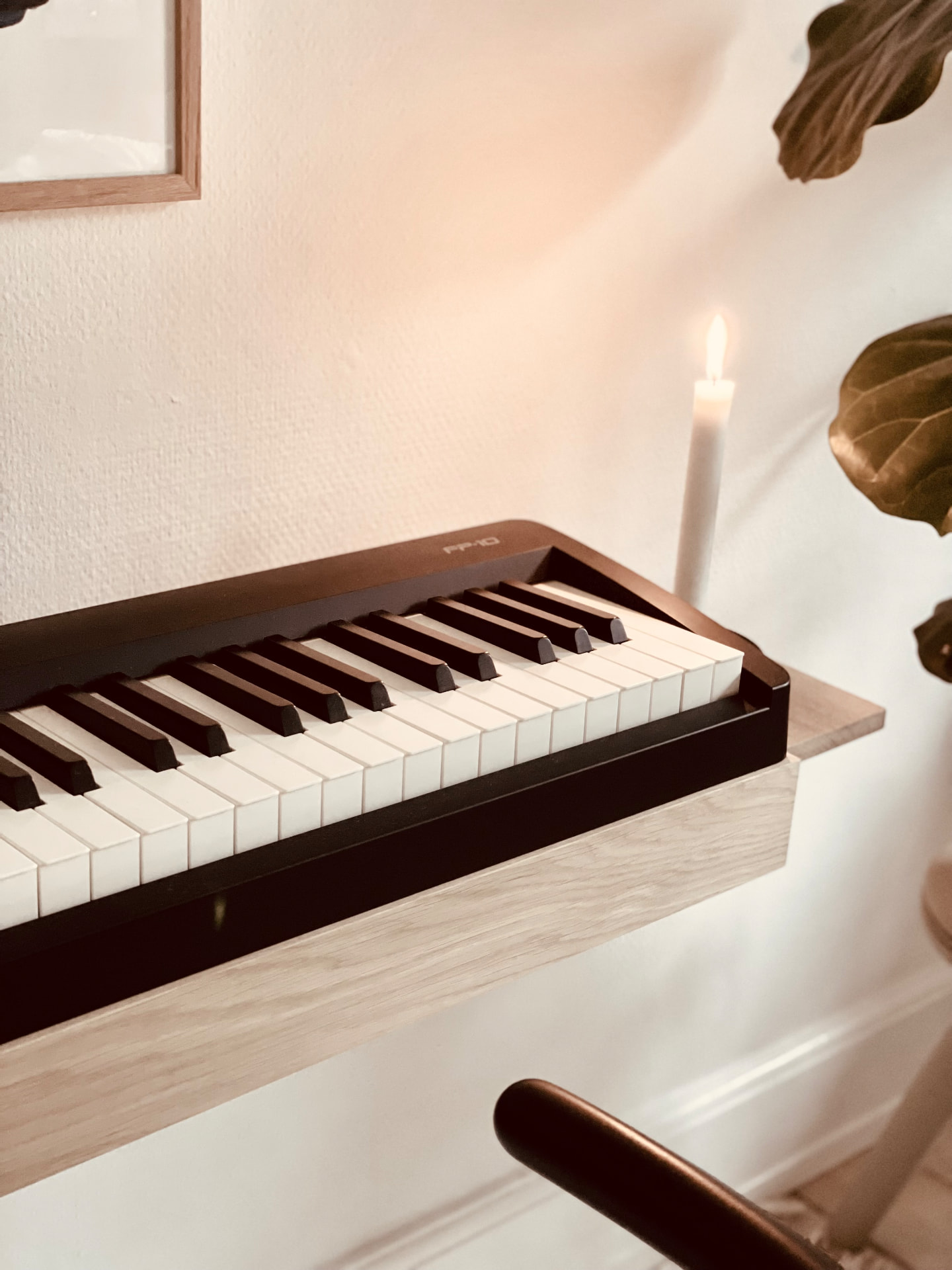 Close-up of the handcrafted solid oak edge of a wall-mounted digital piano stand by candlelight