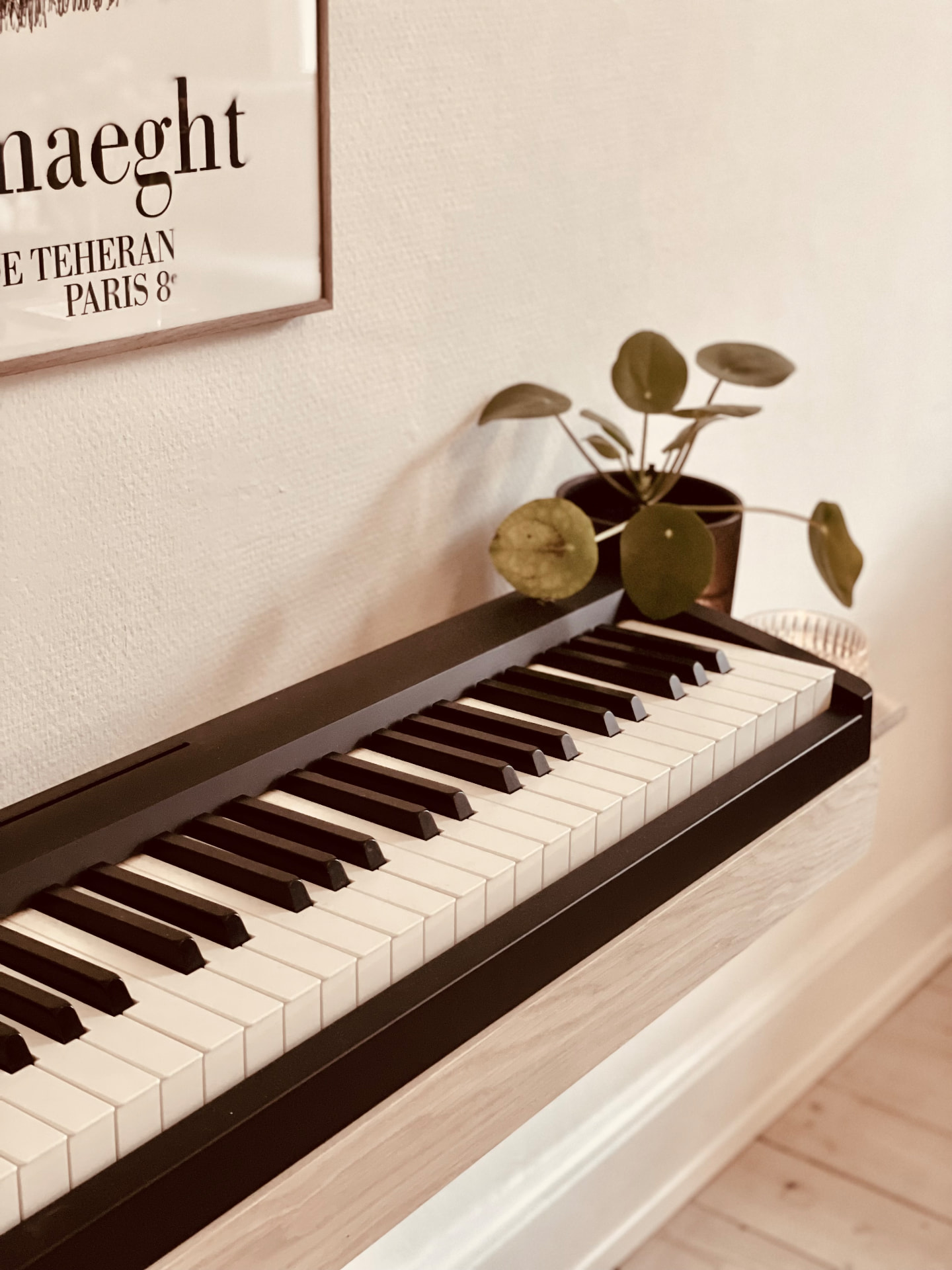 Oak Floating Piano Frame edge detail with digital piano keys and a plant