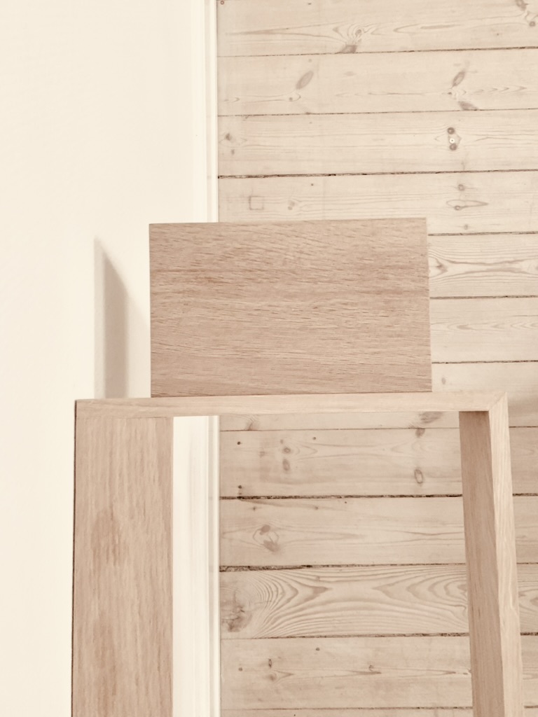 Solid oak wood sample resting on a Floating Piano Frame showing the natural grain and craftsmanship