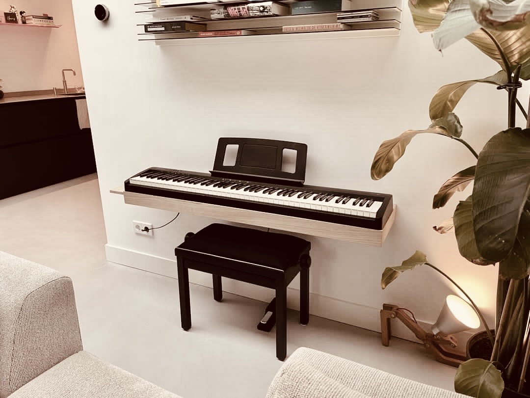 Customer photo of a space-saving oak piano wall shelf in an open-plan living room next to a large plant